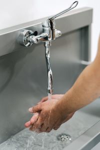 Midsection of man with faucet in bathroom