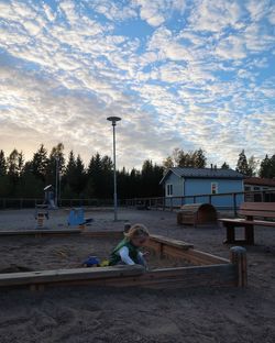 People relaxing at park against sky