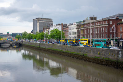 Bridge over river by buildings against sky