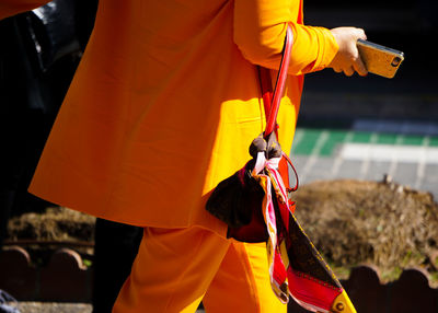 Midsection of woman walking while holding mobile phone