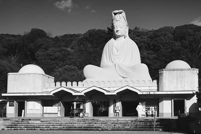 Statue by building against sky