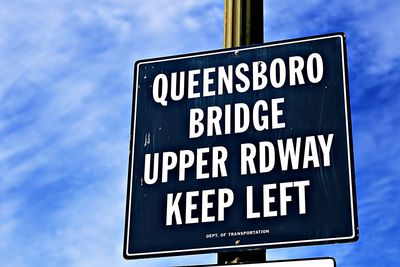 Low angle view of sign board against cloudy sky