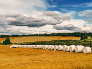 Hay bales on field against sky