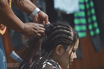 Hairdresser braiding hair of woman