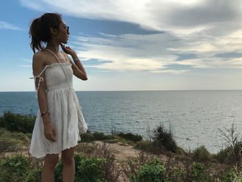 Woman standing at beach against sky