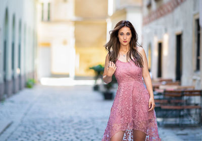 Portrait of beautiful young woman standing on footpath