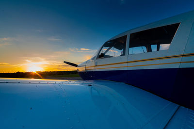 Airplane on airport runway against sky during sunset