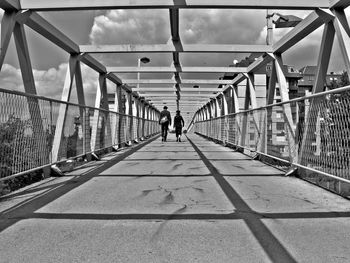 Rear view of man and woman walking on bridge