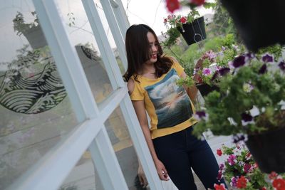 Rear view of woman standing by flowering plants