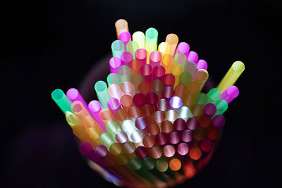 Close-up of multi colored drinking straws over black background