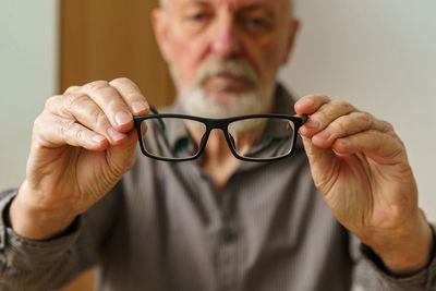 Midsection of man holding eyeglasses