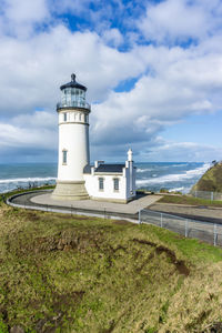 Lighthouse by sea against sky