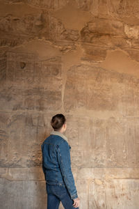Vertical view of unrecognizable young tourist man looking the hieroglyphics art in the egyptian