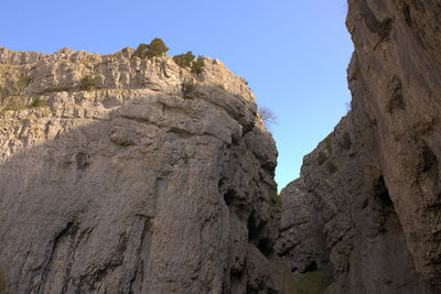 Low angle view of rocky mountains against clear sky