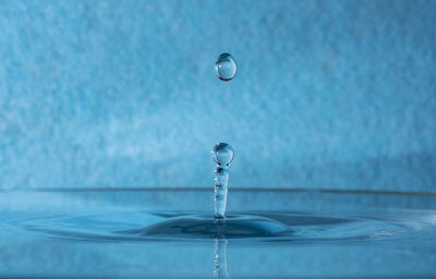 Close-up of drop falling on blue water