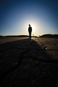 Silhouette man standing on land against sky during sunset