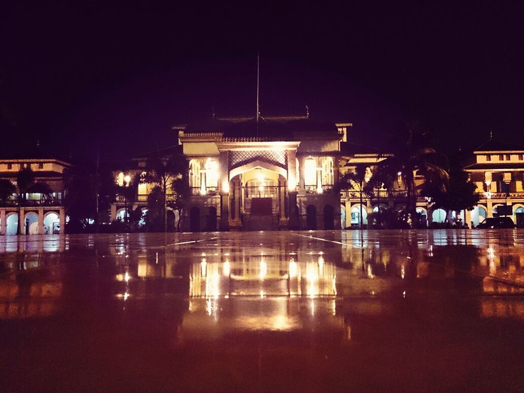 architecture, night, built structure, illuminated, building exterior, city, arch, architectural column, reflection, water, city life, travel destinations, incidental people, street, street light, clear sky, building, facade, outdoors, travel