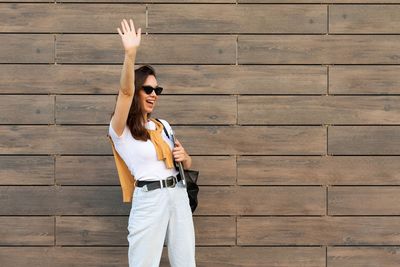 Portrait of young woman standing against wall