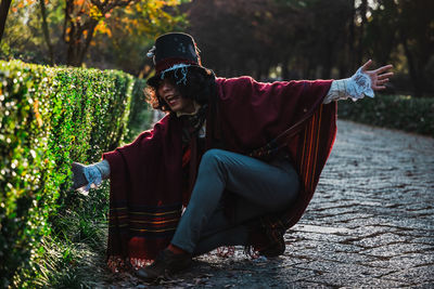 Portrait of man cosplaying mad hatter getting through hedges