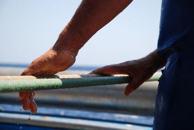 Close-up of hand against sea against clear sky