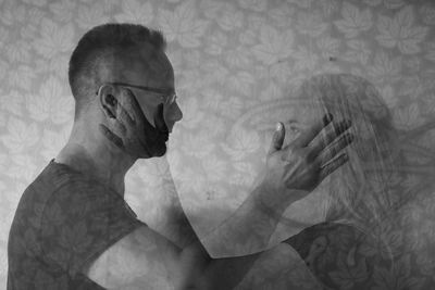 Double exposure of couple touching each other against wallpaper