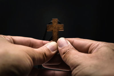 Midsection of person holding cross at home