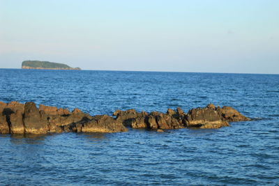 Scenic view of rocks in sea against clear sky