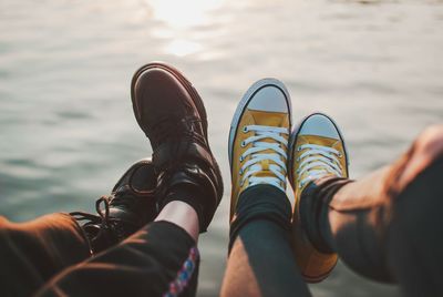 Low section of couple in shoes at sea