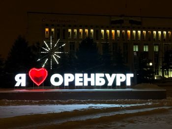 Information sign in illuminated city at night during winter