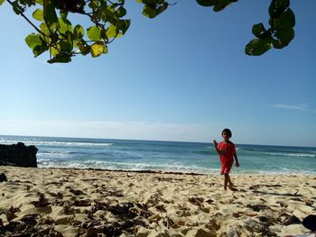 Full length of boy standing on beach against sky