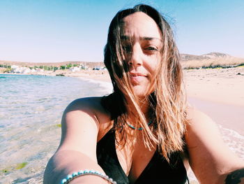 Portrait of beautiful woman at beach against sky