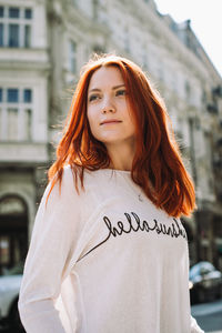 Portrait of beautiful woman standing against city in background