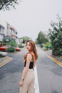 Portrait of woman standing on road in city