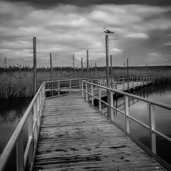 Pier over sea against cloudy sky