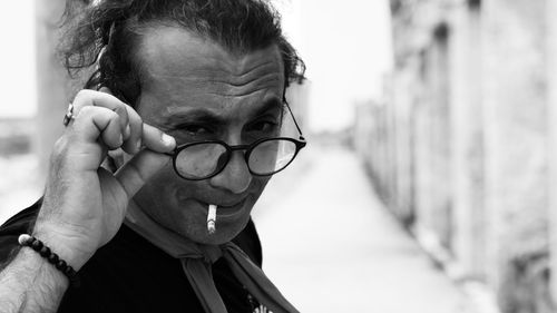 Close-up portrait of man in eyeglasses smoking cigarette outdoors