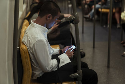 Side view of man using mobile phone in train