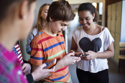 Students using mobile phones in locker room at high school