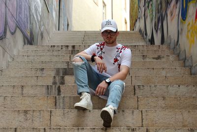 Full length portrait of young man sitting on steps