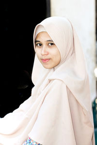 Portrait of beautiful young woman standing against black background