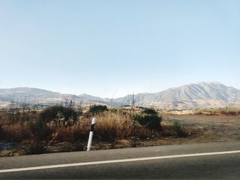 Road by mountains against clear sky