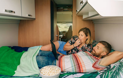 Couple watching a movie lying on the bed of their camper van