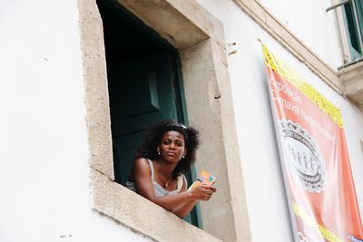 Portrait of happy woman against building