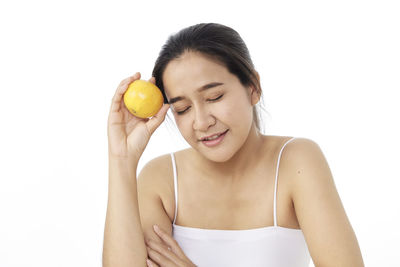 Midsection of woman holding fruit against white background