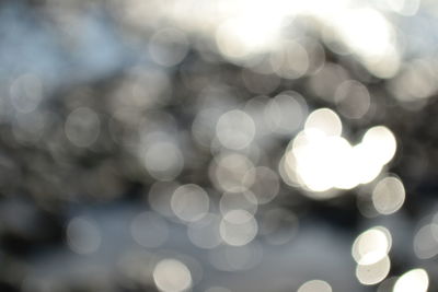 Defocused image of illuminated lights against sky at night