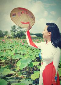 Young woman with umbrella standing against sky