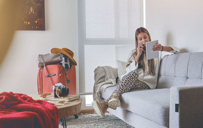 Side view of woman sitting on bed at home