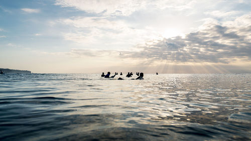 Silhouette people in sea against sky
