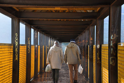 Rear view of people walking on bridge