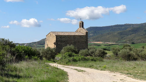 Built structure on field by road against sky