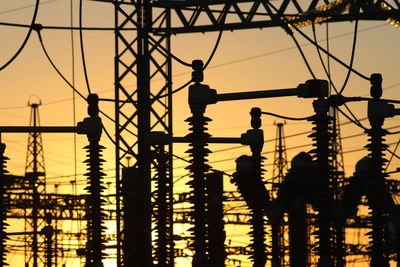 Silhouette transformer against sky during sunset